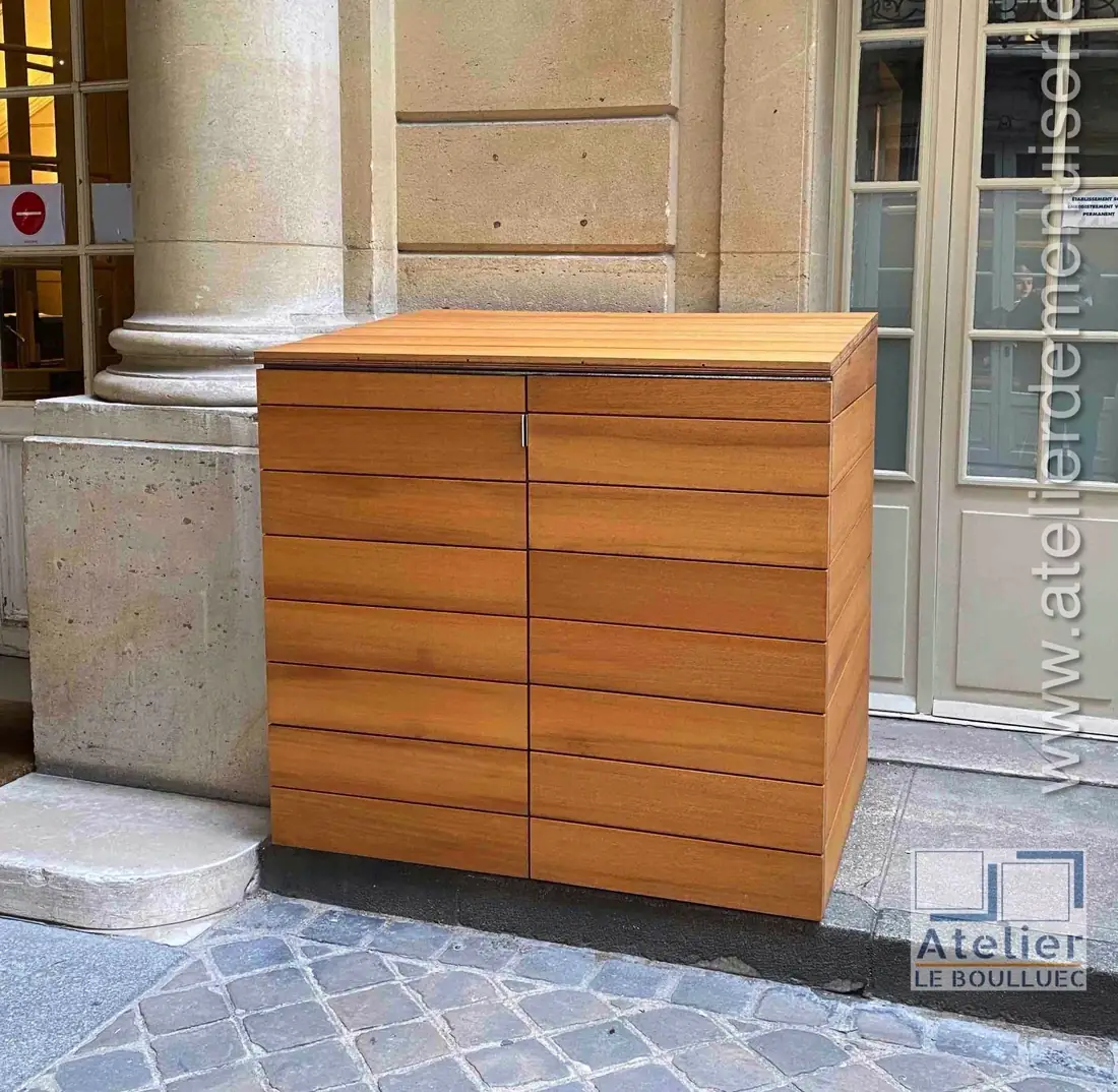 Coffre à conteneurs en lames d’iroko posé sous un porche d’immeuble