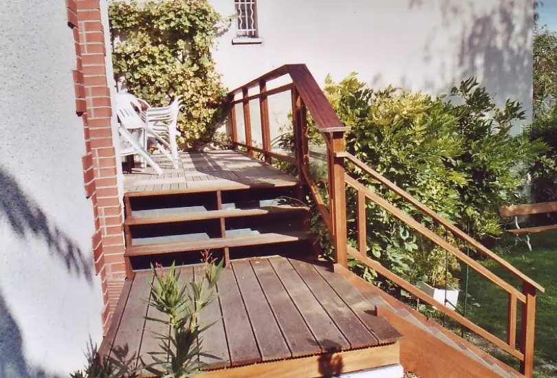Terrasse en lames de bois avec emmarchement et garde-corps à lisses, ouverte sur un jardin