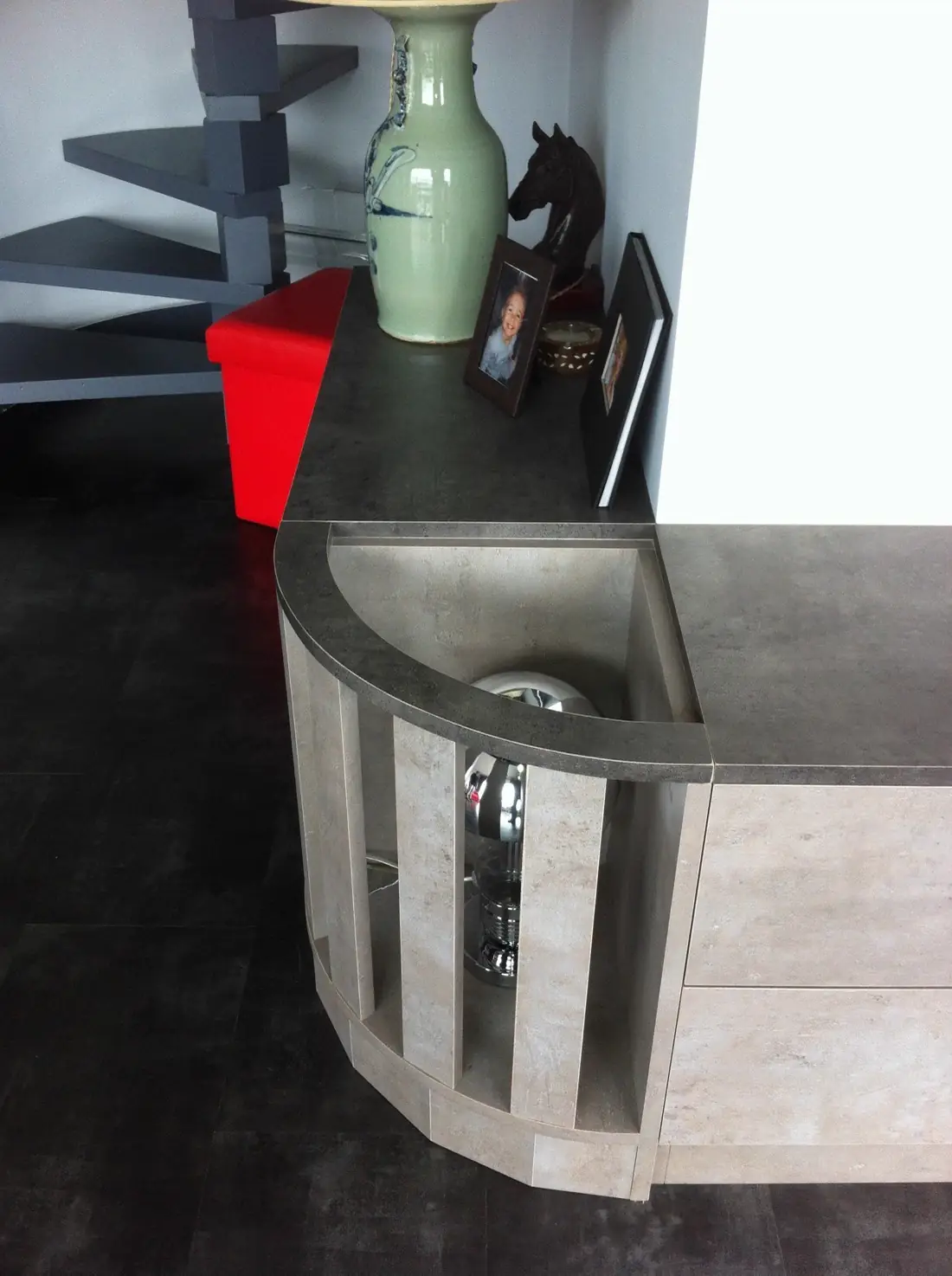 Meuble d’angle arrondi à plateau sombre, avec vitrine latérale